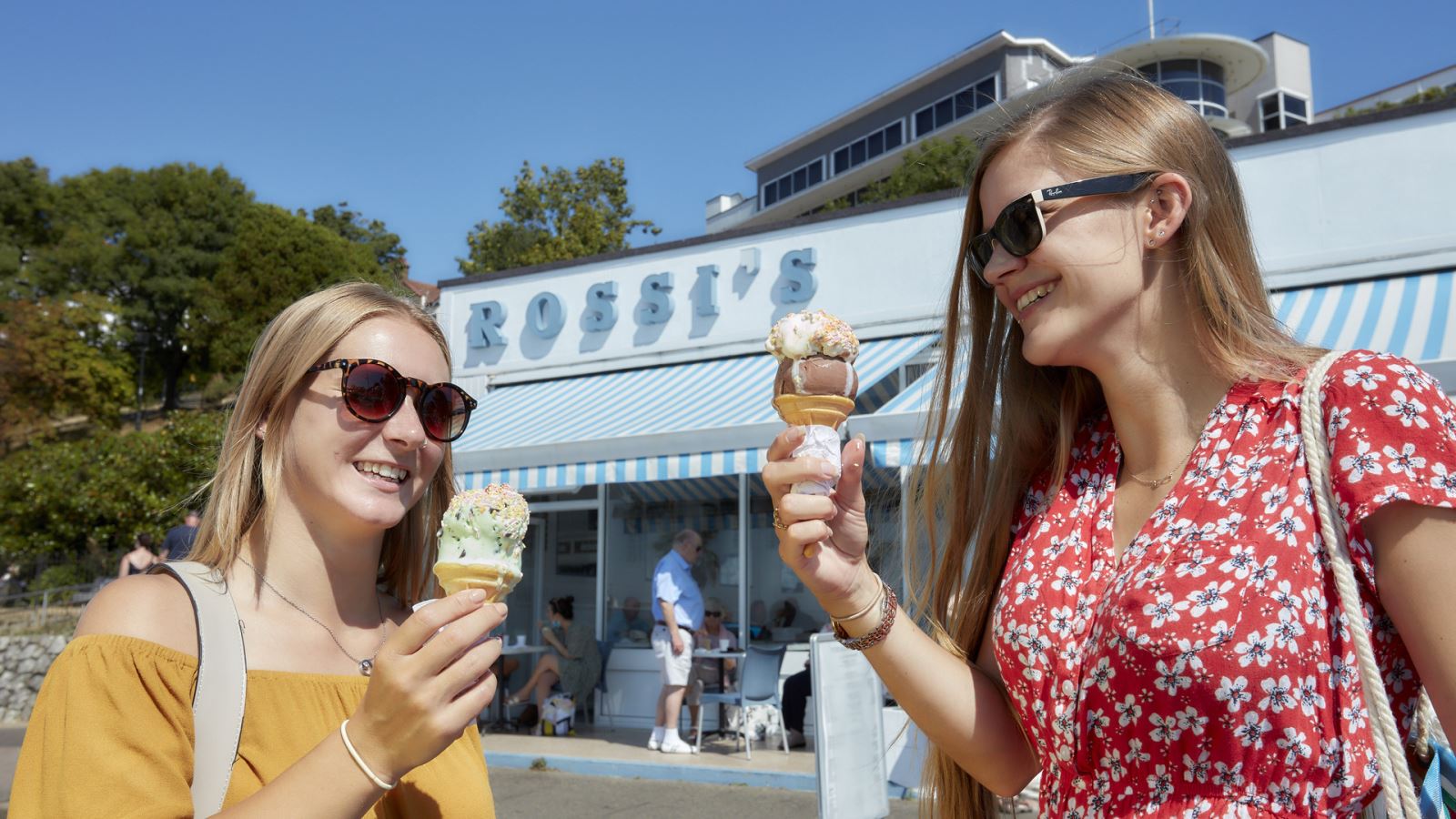 Two women eating ice cream outside Rossi's Ice Cream Parlour in Southend, Essex